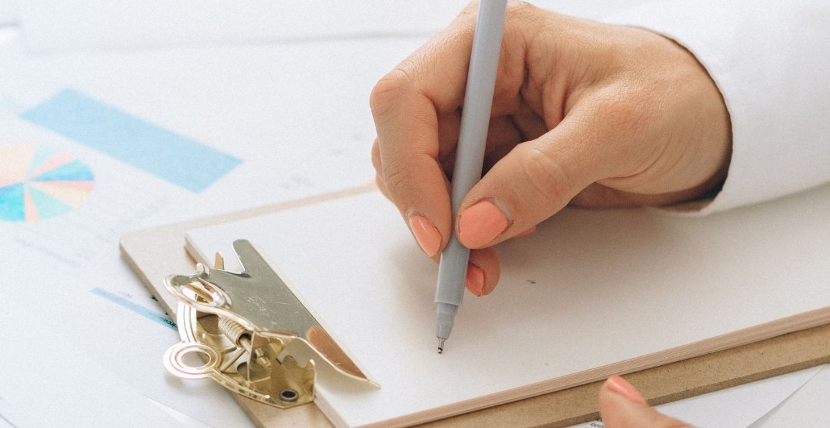 Ruka piše na podlošku iznad financijskih grafikona